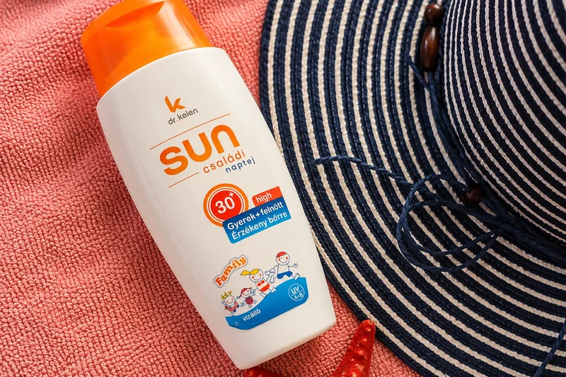Detail opaľovacieho krému s SPF 30 pri klobúku na ružovom uteráku
