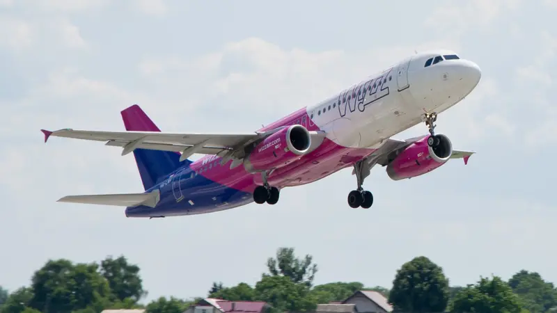 Lietadlo Wizz Air s ružovo-fialovým trupom pri vzlete, podvozok ešte vonku