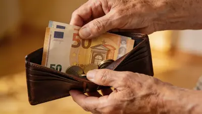 Staršie ruky držia peňaženku s eurami