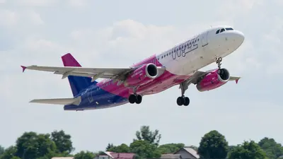 Lietadlo Wizz Air s ružovo-fialovým trupom pri vzlete, podvozok ešte vonku