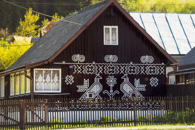 Drevené zrubové domy s bielymi geometrickými vzormi v Čičmanoch